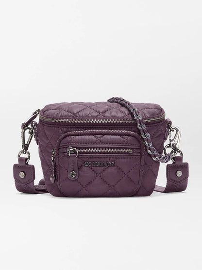 The MZ Wallace Micro Crosby Crossbody Sling in Raisin Oxford is a small quilted purple crossbody bag featuring silver-tone hardware, a front zip pocket, chain and fabric strap, and an “MZ Wallace” logo plaque. Crafted from recycled nylon, this compact sling offers hands-free convenience for carrying your essentials on the go.