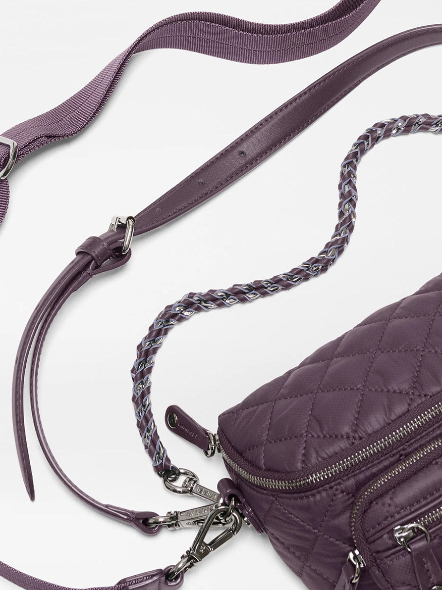Close-up of the MZ Wallace Micro Crosby Crossbody Sling in Raisin Oxford, featuring quilted purple recycled Oxford nylon, a braided strap, silver hardware, and a detachable fabric shoulder strap for hands-free carry, set against a white background.