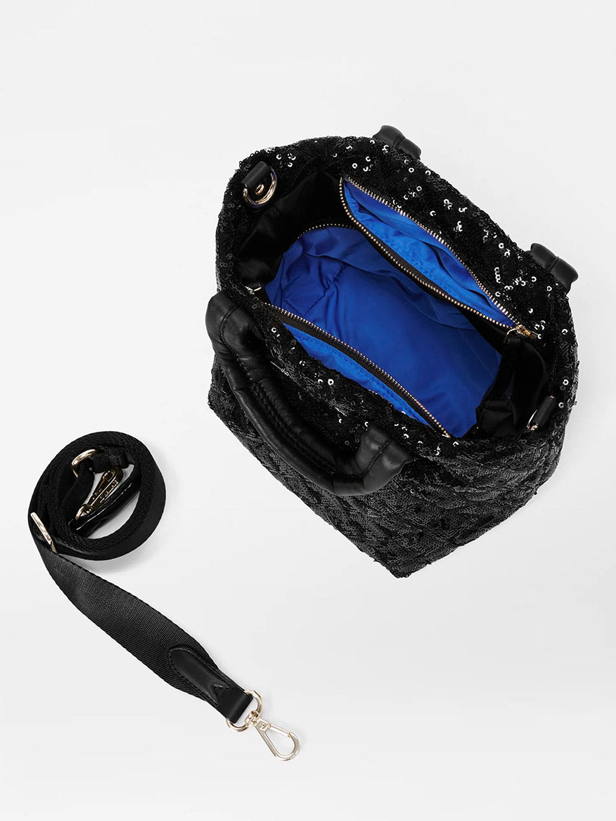 The MZ Wallace Micro Metro Tote Deluxe in Black Sequin, featuring an Italian leather trim, includes a detachable crossbody strap. Open it to reveal its blue interior and convenient zipper compartment, offering the perfect blend of glamour and functionality.