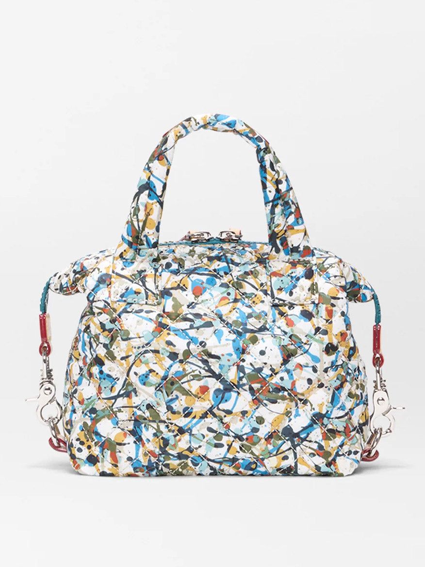 The MZ Wallace Micro Sutton in Club Paint Oxford is a quilted nylon bag with a multicolored abstract paint-splatter pattern, double handles, and removable shoulder strap clips, shown on a plain white background.
