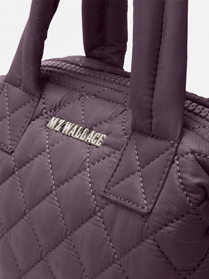 Close-up of the MZ Wallace Micro Sutton in Raisin Oxford, a compact crossbody purse made from quilted recycled nylon with soft handles and a metallic-stitched "MZ WALLACE" logo.