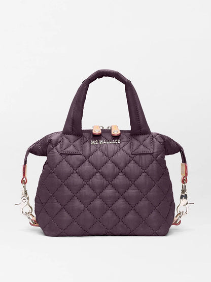 The MZ Wallace Micro Sutton in Raisin Oxford is a small quilted handbag with short handles, silver hardware, and a detachable strap—combining style and versatility in a compact crossbody design against a white background.