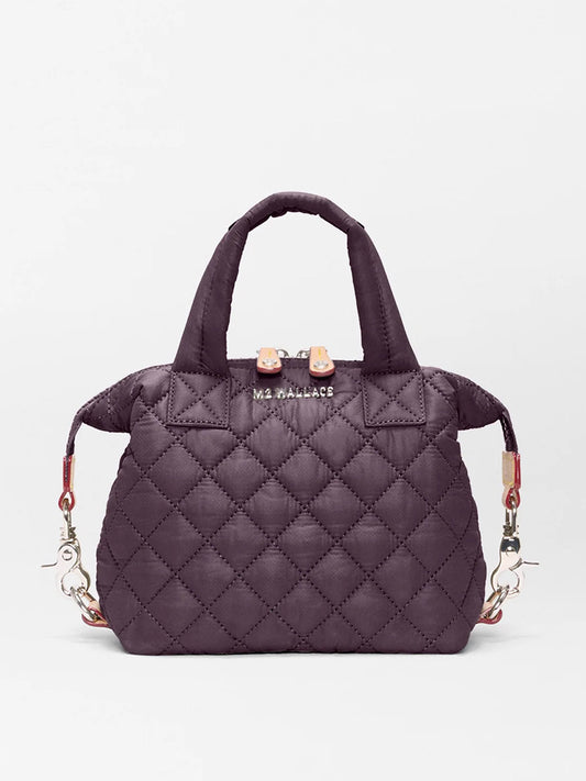 The MZ Wallace Micro Sutton in Raisin Oxford is a small quilted handbag with short handles, silver hardware, and a detachable strap—combining style and versatility in a compact crossbody design against a white background.