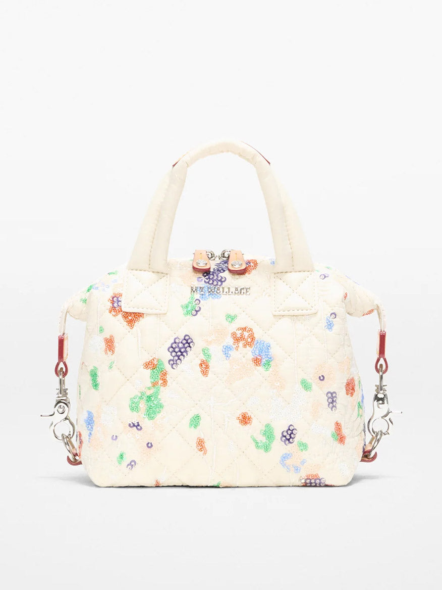 The MZ Wallace Micro Sutton in Eden Sequin Oxford is a cream quilted handbag featuring multicolored beaded floral designs, two short handles, a detachable crossbody strap, and silver hardware.