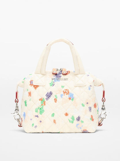 The MZ Wallace Micro Sutton in Eden Sequin Oxford is a cream quilted handbag featuring multicolored beaded floral designs, two short handles, a detachable crossbody strap, and silver hardware.