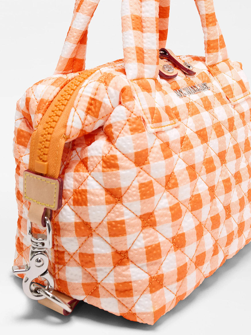 Close-up of the MZ Wallace Micro Sutton in Sunset Orange Gingham Oxford, made from recycled nylon with a checkered pattern, zip closure, metal hardware, dual handles, and an adjustable crossbody strap.