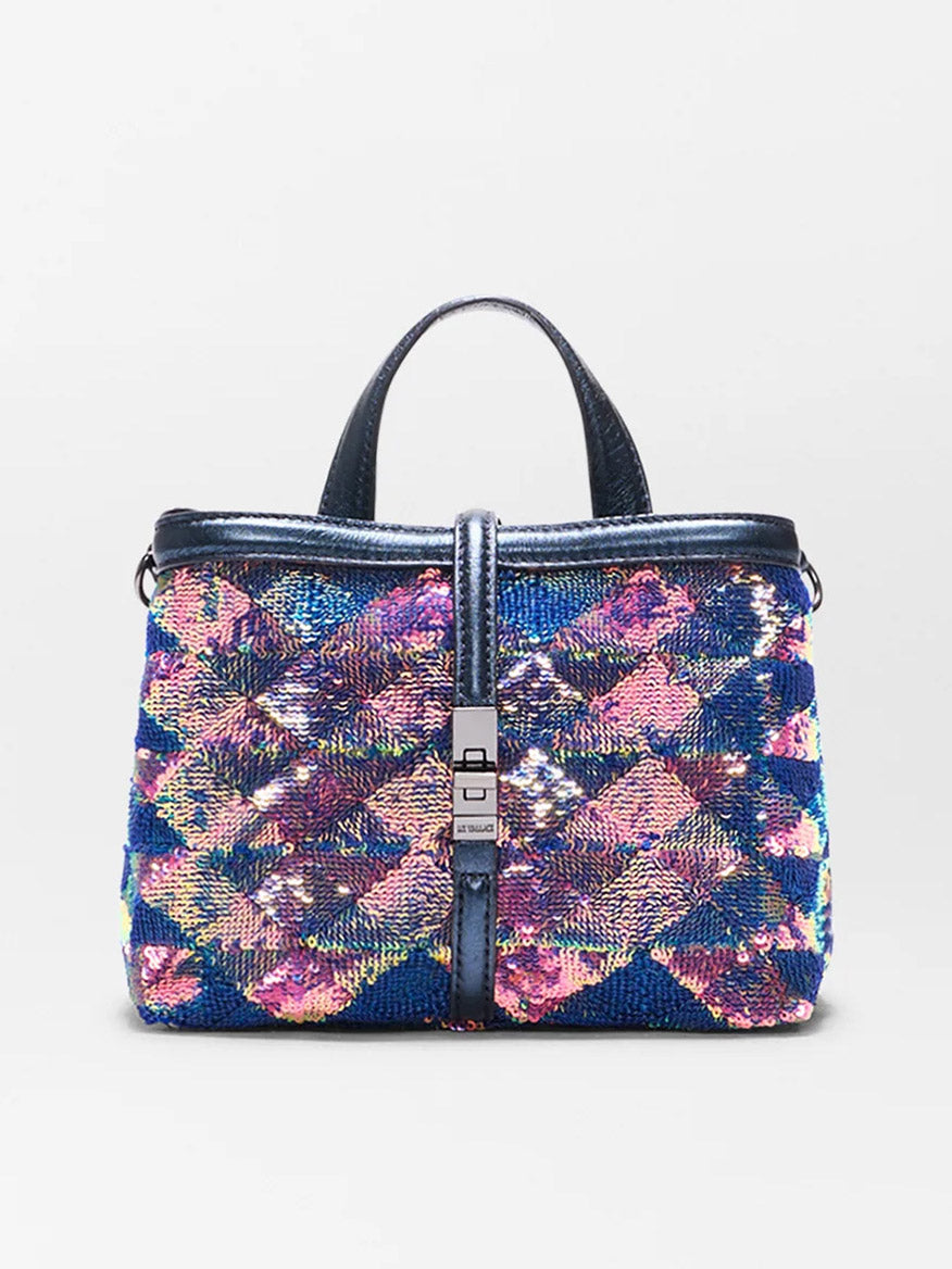 The MZ Wallace Mini Astor Top Handle in Aurora Sequin is a small bag with a blue base, colorful sequins in pink, yellow, and purple, short handles, an Italian leather strap, and a central metallic clasp.