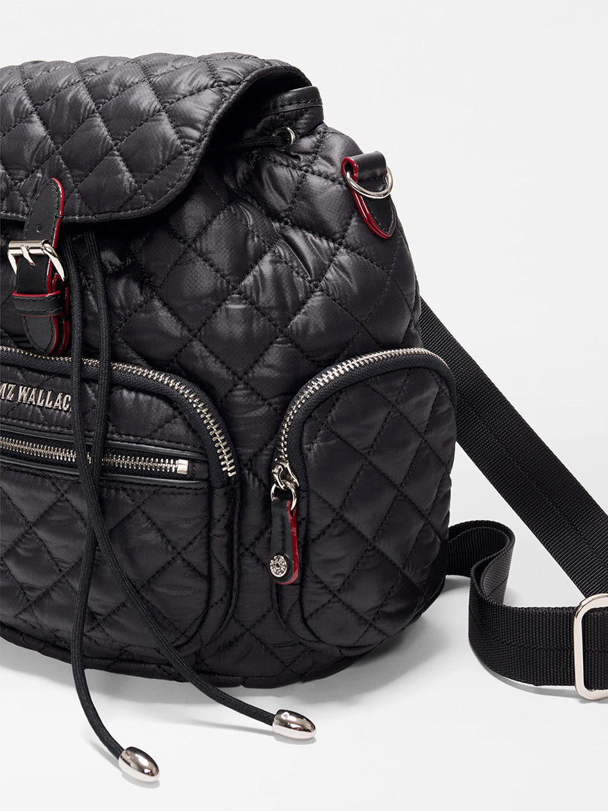 The MZ Wallace Mini Crosby Backpack in Black Oxford is made from recycled nylon with silver zippers, a front pocket, black drawstrings, and an adjustable strap, shown against a plain white background.