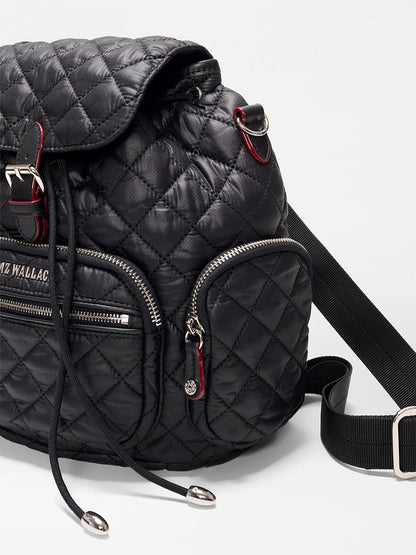The MZ Wallace Mini Crosby Backpack in Black Oxford is made from recycled nylon with silver zippers, a front pocket, black drawstrings, and an adjustable strap, shown against a plain white background.