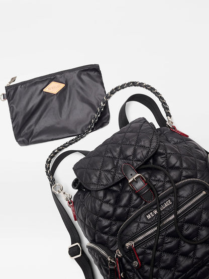 The MZ Wallace Mini Crosby Backpack in Black Oxford, featuring a quilted design, zippered pockets, and chain details, is displayed beside a matching black zip pouch against a plain background.
