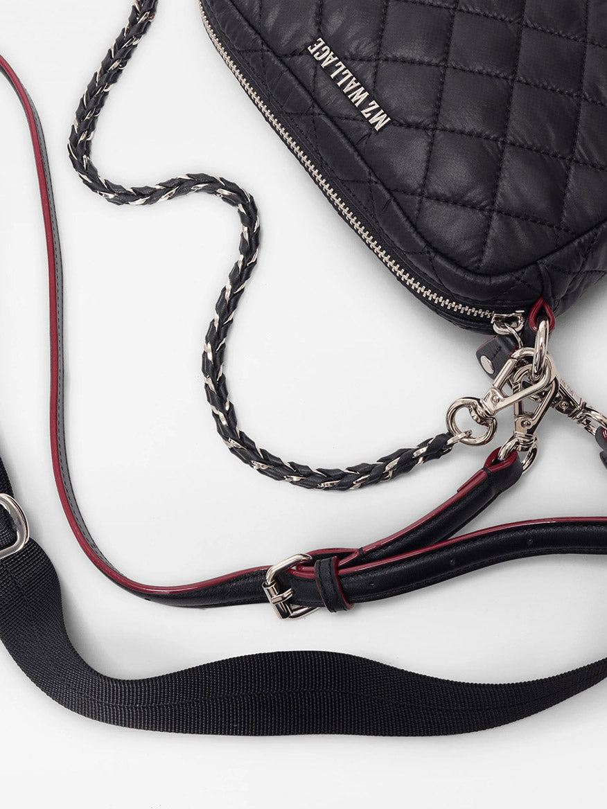 The MZ Wallace Mini Crosby Crossbody II in Black Oxford, featuring quilted design, Italian leather trim, silver zipper, metal hardware, and a chain-leather strap, rests on a white surface.