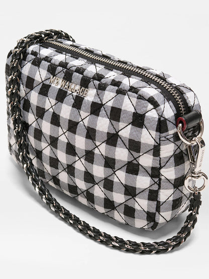 The MZ Wallace Mini Crosby Crossbody II in Black/White Gingham Oxford features quilted material, a chain and adjustable strap, zip closure, and "MZ WALLACE" on the front.