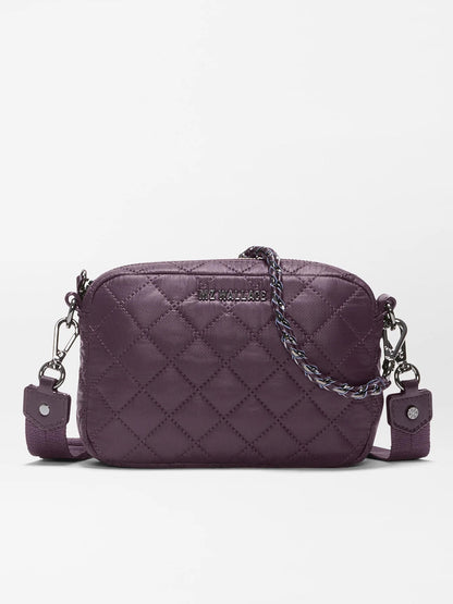 The MZ Wallace Mini Crosby Crossbody II in Raisin Oxford is a small, quilted purple bag made from recycled Oxford nylon, featuring detachable straps, silver hardware, and a braided detail on the zipper pull, shown against a plain white background.