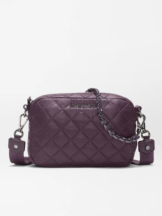 The MZ Wallace Mini Crosby Crossbody II in Raisin Oxford is a small, quilted purple bag made from recycled Oxford nylon, featuring detachable straps, silver hardware, and a braided detail on the zipper pull, shown against a plain white background.
