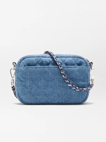 The MZ Wallace Mini Crosby Crossbody II in True Blue Denim is a small rectangular bag with quilted details, silver hardware, and a detachable chain strap, shown against a plain white background.