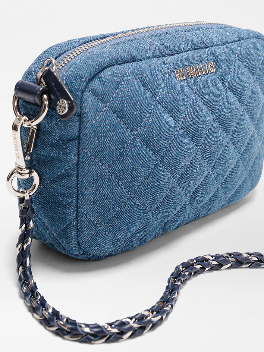 The MZ Wallace Mini Crosby Crossbody II in True Blue Denim is a quilted blue denim bag with a silver zipper, detachable chain strap, and front logo detailing.