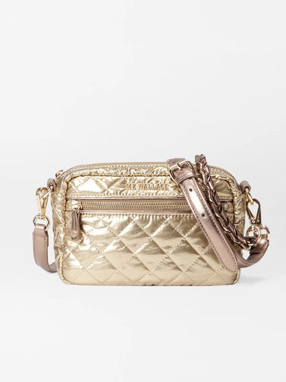 The MZ Wallace Mini Crosby in Antique Gold Metallic Oxford, made from luxurious Italian leather, boasts a quilted design and includes a front zipper pocket along with a versatile chain that can be used as a crossbody strap.