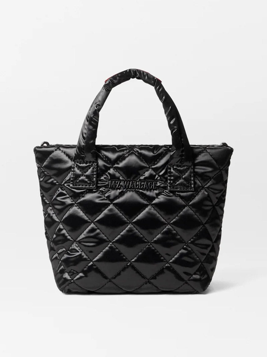 Introducing the MZ Wallace Petite Metro Tote Deluxe in Black Liquid Oxford, a chic quilted handbag from the Metro Tote collection. It showcases a sophisticated diamond pattern and a subtle logo on the front. This stylish piece offers versatility with its two handles and an adjustable nylon crossbody strap for diverse carrying options.