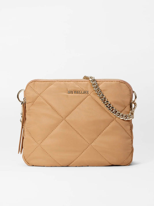 The MZ Wallace Quilted Madison Crossbody in Caramel Bedford is a tan handbag made from recycled nylon, featuring a chic chain strap, tassel, Italian leather trim, and a subtle front logo for an eco-friendly and stylish accessory.