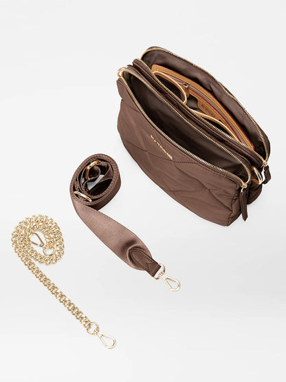 Introducing the MZ Wallace Quilted Madison Crossbody in Walnut Bedford, displayed open to reveal its compartments. This stylish handbag features gold zippers, a detachable brown strap, and a detachable gold chain strap. It is crafted from recycled nylon and elegantly showcased on a white surface.