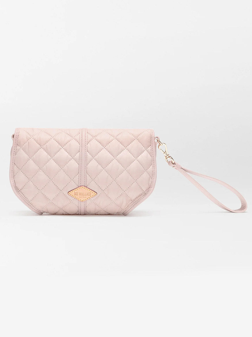 The MZ Wallace Small Astor Convertible Clutch in City Pink Oxford features a light pink quilted design, Italian leather trim, gold logo plate, and a detachable wrist strap, shown against a plain white background.