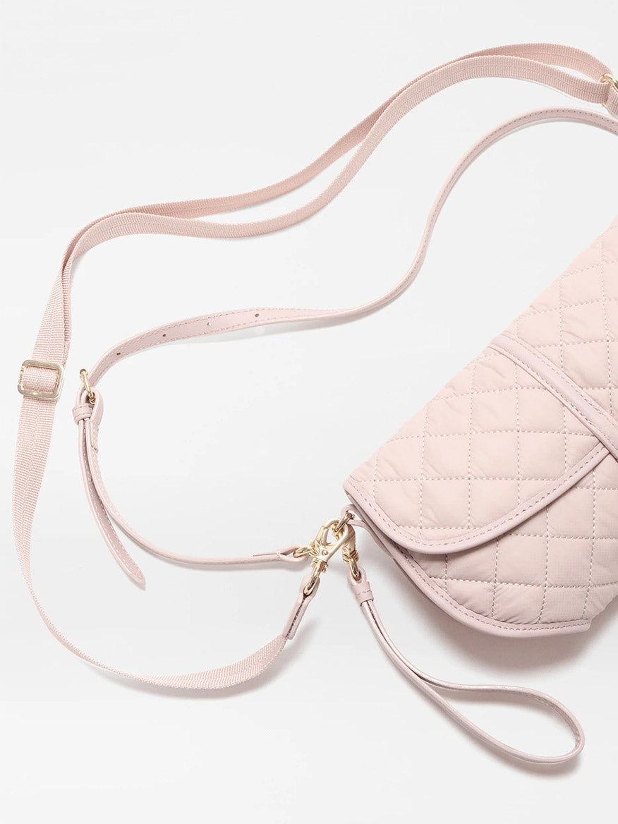 The MZ Wallace Small Astor Convertible Clutch in City Pink Oxford features light pink quilted fabric, gold hardware, Italian leather trim, a removable adjustable strap, and a smaller strap, shown on a white background.