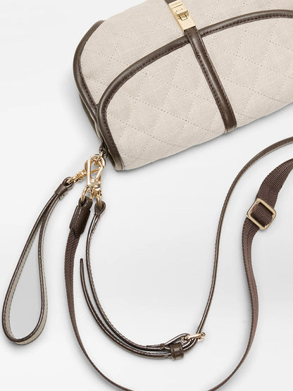 The MZ Wallace Small Astor Convertible Clutch in Sandy Linen features a beige quilted design, dark brown straps, Italian leather trim, gold hardware, and an adjustable shoulder strap. Shown on a white background.