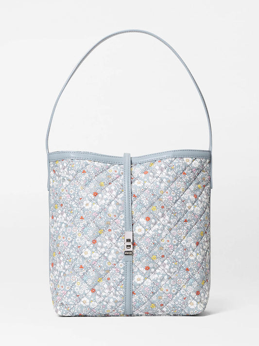 The MZ Wallace Small Astor Hobo in June's Meadow Liberty Fabric is a quilted light blue floral shoulder bag with a single strap and small silver clasp, shown against a plain white background.
