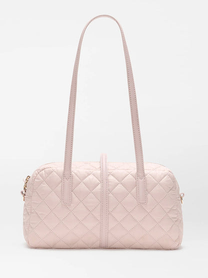 The MZ Wallace Small Astor Satchel in City Pink Oxford, a light pink quilted nylon bag with Italian leather trim, double shoulder straps, and gold-tone hardware, is displayed against a plain white background.