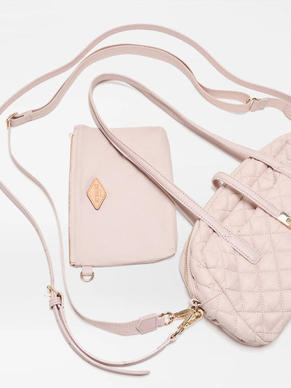 The MZ Wallace Small Astor Satchel in City Pink Oxford, featuring a light pink quilted nylon body with Italian leather trim and gold hardware, is paired with a matching zippered pouch and displayed against a white background.