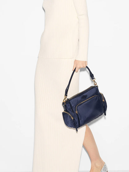 A person in a white dress holding a MZ Wallace Small Chelsea Crossbody in Dawn Bedford.
