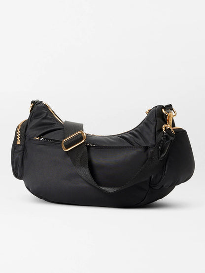 The MZ Wallace Small Chelsea Shoulder in Black Bedford is a black hobo-style handbag made from Italian leather, featuring gold hardware, zippers, and an adjustable strap.