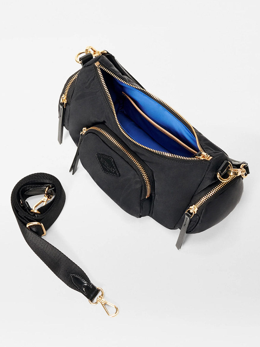 The MZ Wallace Small Chelsea Shoulder in Black Bedford is a crossbody bag made from Italian leather, featuring multiple zippered compartments and a detachable strap. It has a blue fabric lining and elegant gold hardware accents.