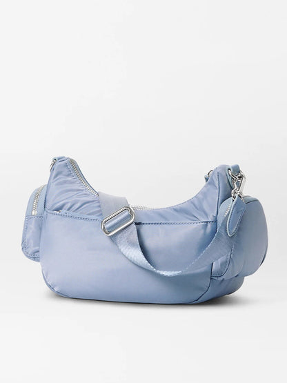 The MZ Wallace Small Chelsea Shoulder in Stone Blue Bedford features a sculpted shape, Italian leather, zippered top, adjustable crossbody strap, and a handy side pocket. Set against a plain white background.