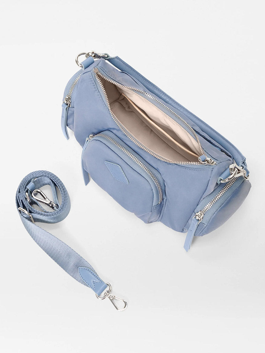 The MZ Wallace Small Chelsea Shoulder in Stone Blue Bedford is a crossbody bag made of Italian leather, with multiple zip compartments and a detachable strap, and shown open to display the interior lining.