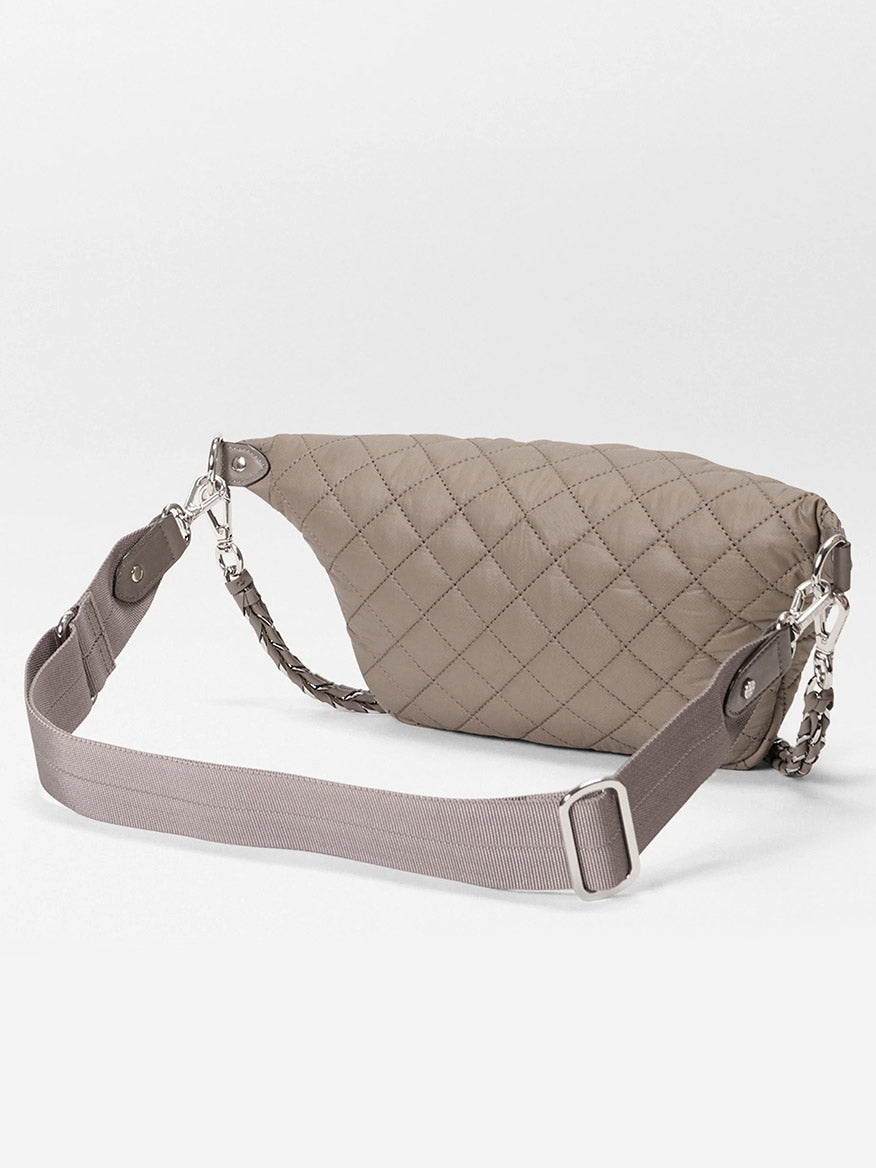 The MZ Wallace Small Crosby Sling Bag in Morning Dove Oxford, featuring a quilted design with a wide adjustable strap and silver hardware, is displayed against a white background.