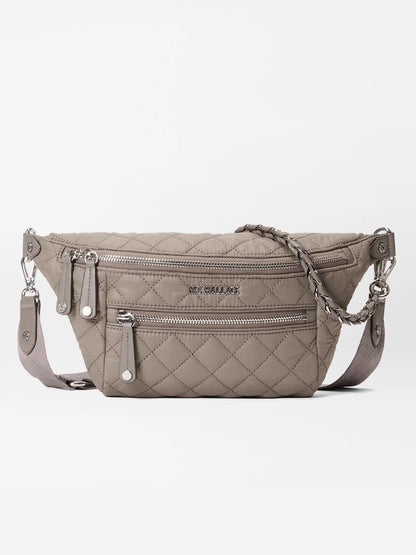 The MZ Wallace Small Crosby Sling Bag in Morning Dove Oxford is a quilted crossbody with two zippered compartments, a braided zipper pull, and an adjustable shoulder strap, shown on a white background.