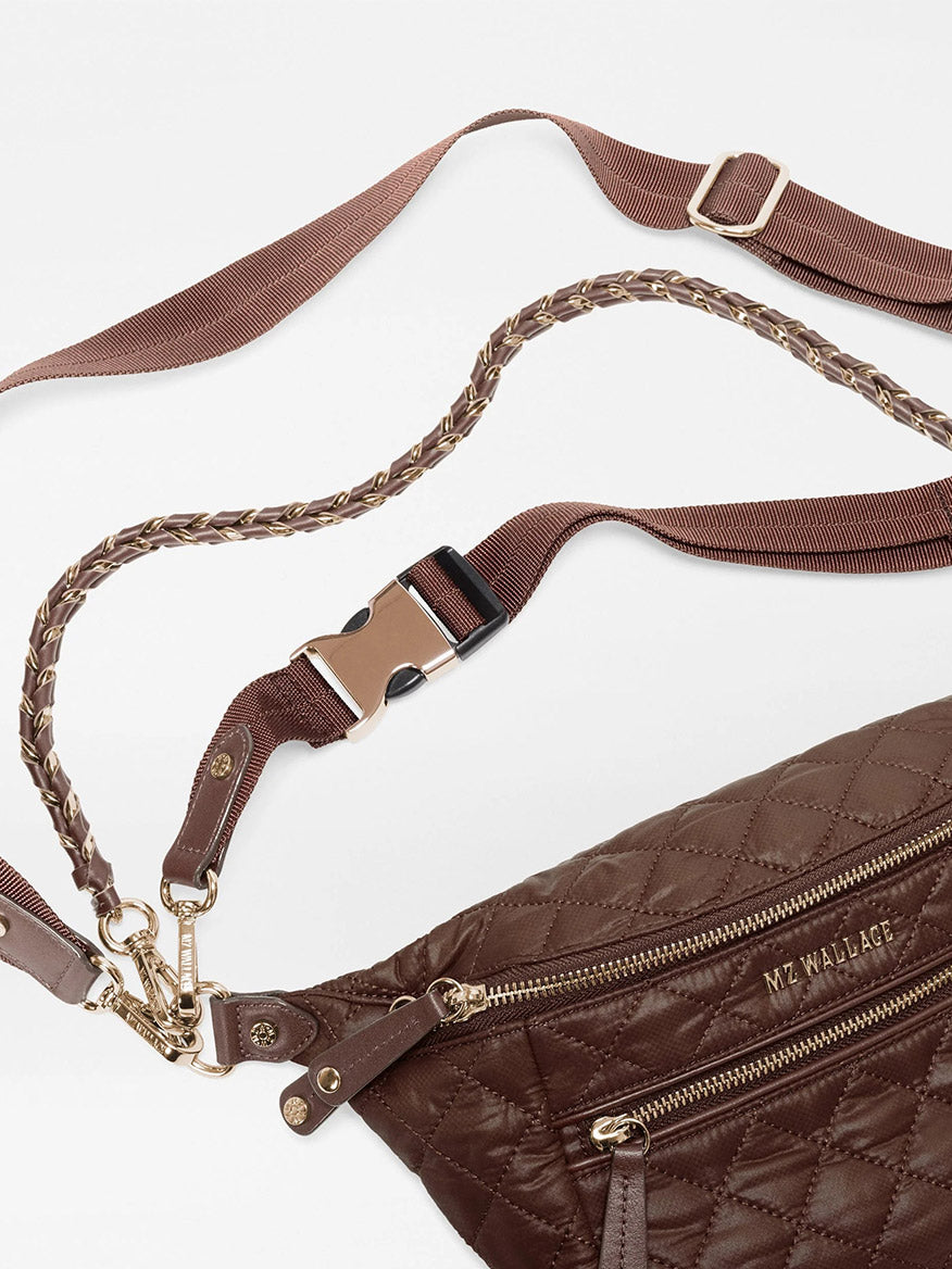 The MZ Wallace Small Crosby Sling Bag in Walnut Oxford is a brown quilted recycled nylon sling bag with a braided, adjustable strap and a side-release buckle.