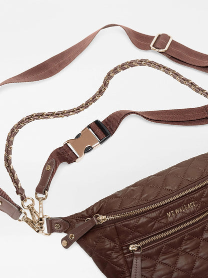 The MZ Wallace Small Crosby Sling Bag in Walnut Oxford is a brown quilted recycled nylon sling bag with a braided, adjustable strap and a side-release buckle.
