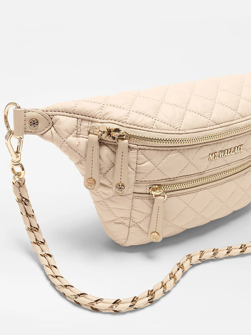 The MZ Wallace Small Crosby Sling Bag in Buff Oxford features a beige quilted design, gold zippers, a chain strap, and the signature MZ Wallace logo on the front.