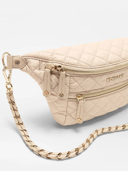 The MZ Wallace Small Crosby Sling Bag in Buff Oxford features a beige quilted design, gold zippers, a chain strap, and the signature MZ Wallace logo on the front.