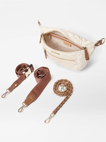 The MZ Wallace Small Crosby Sling Bag in Sandshell Oxford with Brown features a cream quilted design, gold hardware, an adjustable crossbody strap, and two detachable options—a brown web strap and a braided leather strap.