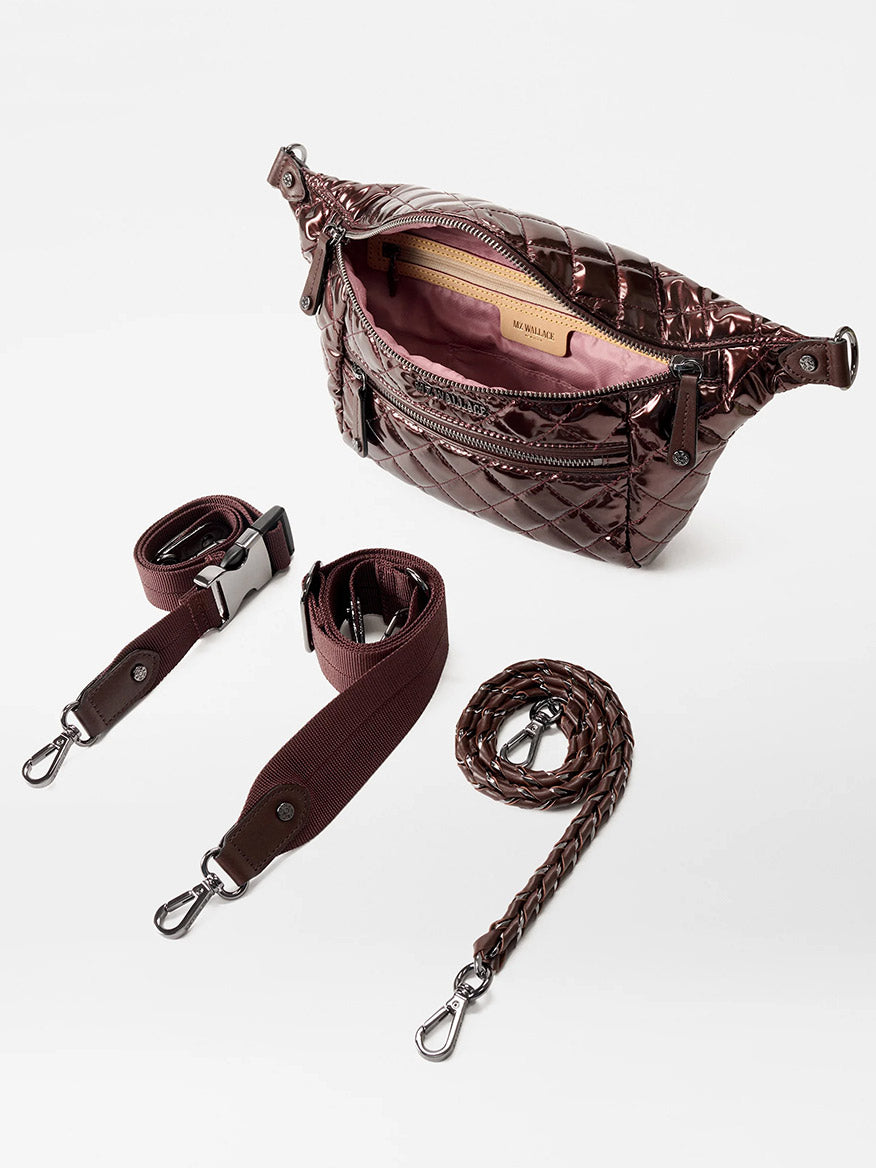The MZ Wallace Small Crosby Sling Bag in Bordeaux Lacquer Oxford is a quilted crossbody with pink interior, shown with two detachable straps—one woven, one flat—on a white background.
