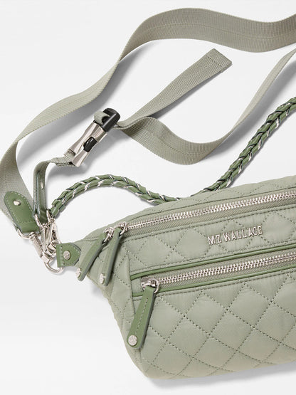 The MZ Wallace Small Crosby Sling Bag in Agave Green Oxford features a quilted design, silver zippers, braided accents, and the "MZ WALLACE" logo on the front.