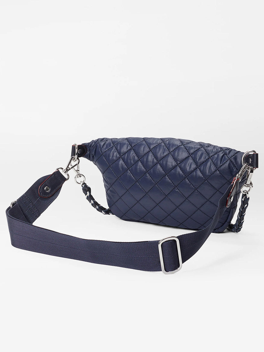 The MZ Wallace Small Crosby Sling Bag in Dawn Oxford features a navy blue quilted design, a wide adjustable strap, and silver hardware, shown against a plain white background.