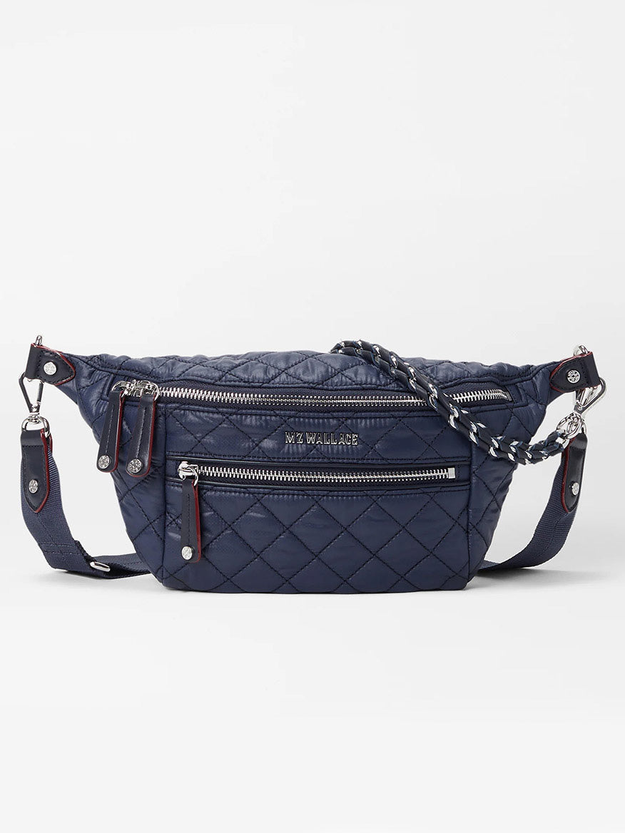 The MZ Wallace Small Crosby Sling Bag in Dawn Oxford, featuring silver zippers, a front zip pocket, and a detachable strap, is displayed against a white background.