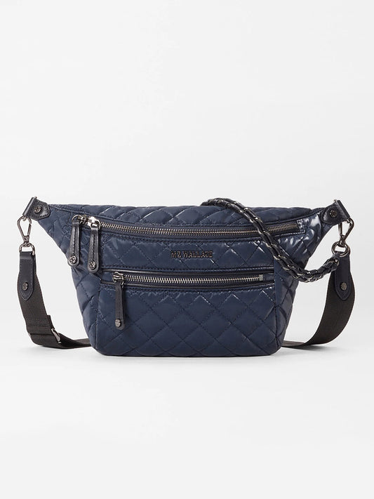 The MZ Wallace Small Crosby Sling Bag in Ink Liquid Oxford is a quilted crossbody with multiple zippered compartments and a detachable black strap, shown against a plain white background.