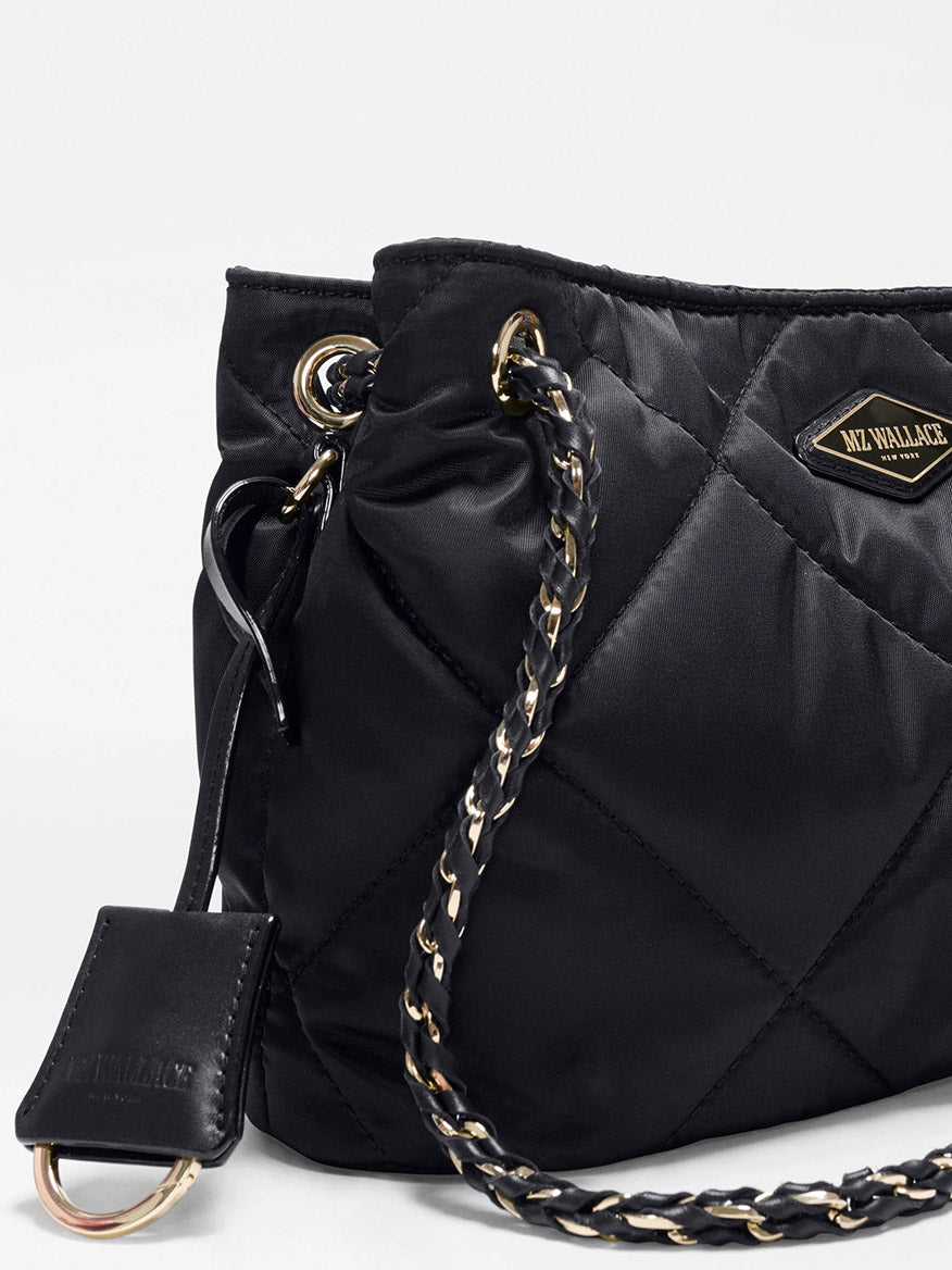 The MZ Wallace Small Frankie Tote in Black Bedford is a black quilted nylon bag with gold and black chain straps, a metal ring detail, an adjustable crossbody strap, and a prominent “MZ Wallace” logo patch on the front.