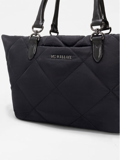 The MZ Wallace Small Madison E/W Tote in Black Bedford is a black quilted handbag with Italian leather trim, black handles, metal hardware, a slim east–west silhouette, and the "MZ WALLACE" logo on the front.