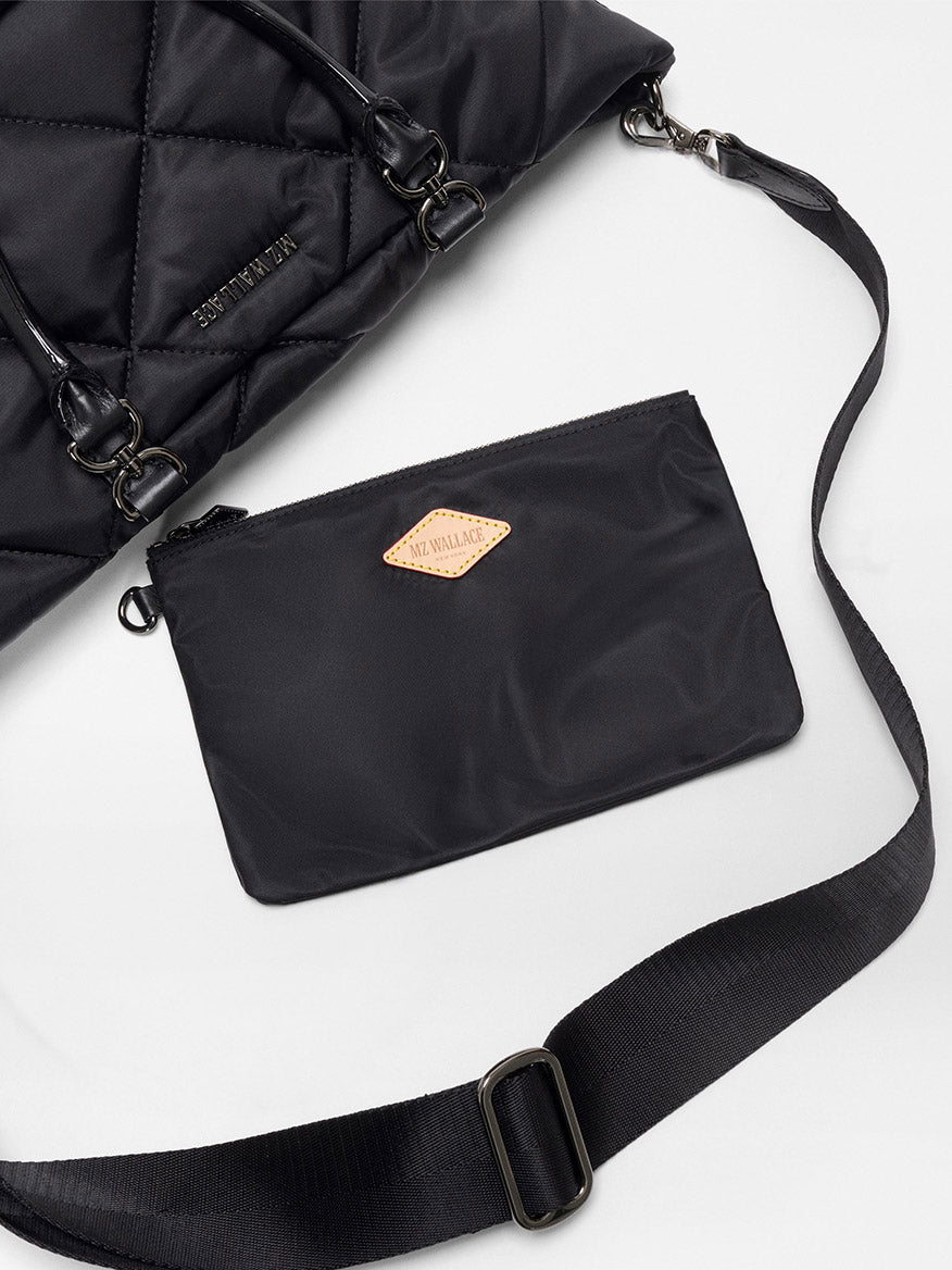 The MZ Wallace Small Madison E/W Tote in Black Bedford features a quilted design, Italian leather trim, an adjustable crossbody strap, and a detachable zippered pouch, displayed on a flat white surface.